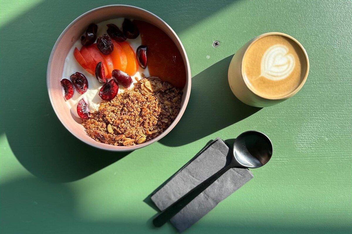 A bowl of granola next to a cup of coffee