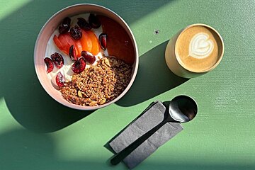 A bowl of granola next to a cup of coffee
