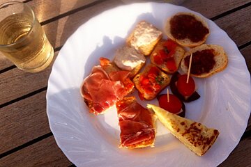 a glass of wine & a plate of tapas on the deck of a boat