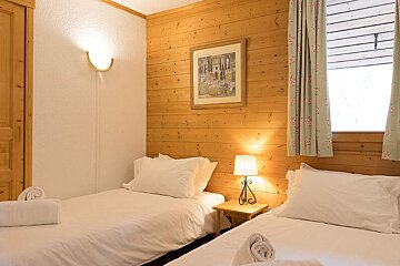 A bedroom with two beds and a picture on the wall
