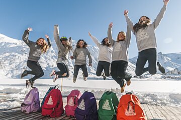 A group of women jumping in the air wearing sweatshirts that say big smile