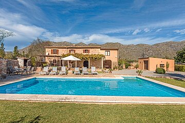 A large swimming pool in front of a house with mountains in the background