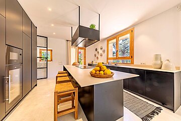 A kitchen with black cabinets and a large island with a bowl of lemons on it