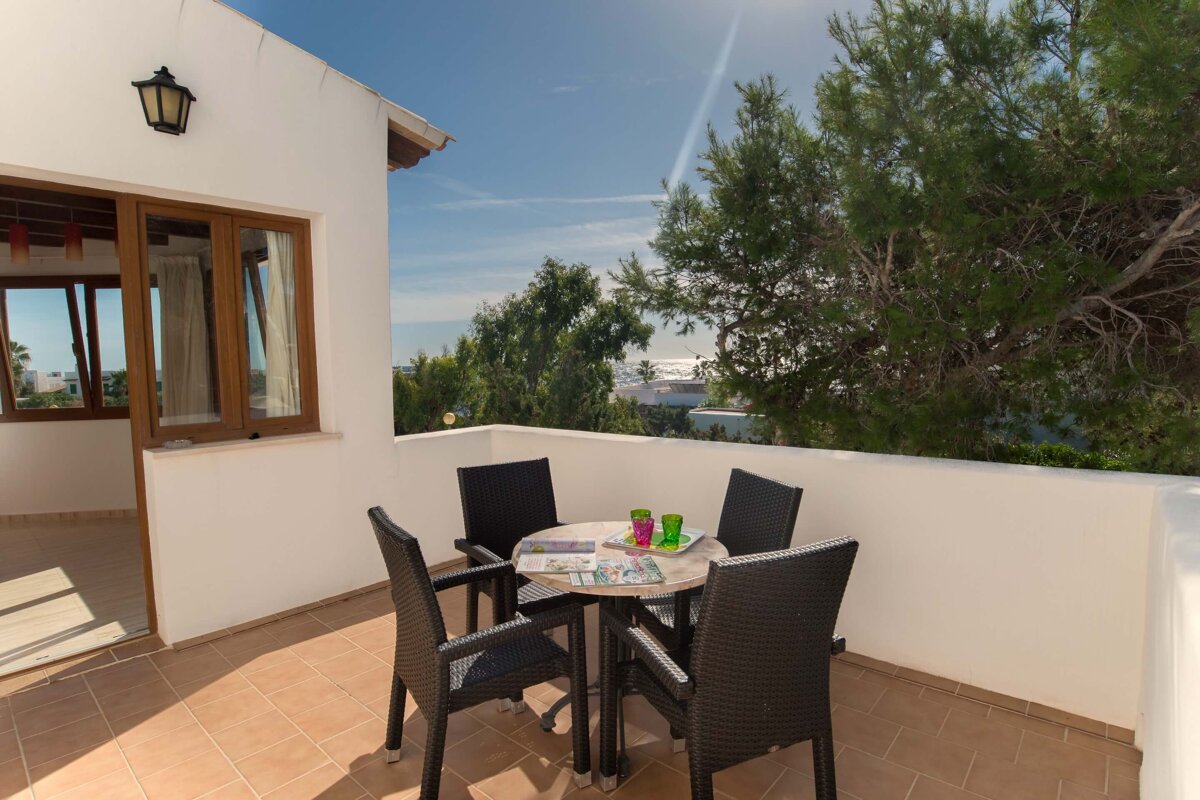 A table and chairs on a balcony with a view of the ocean