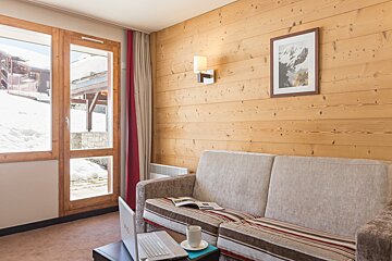 A living room with a couch a laptop and a picture on the wall