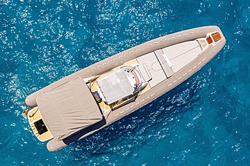 Aerial view of a sleek grey inflatable boat floating on vibrant, sparkling blue water.