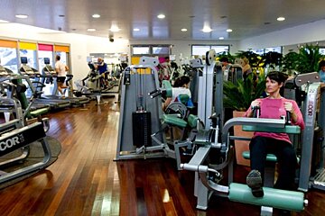 A woman sits on a machine in a gym that says precor