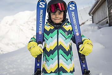 A young boy holding a pair of salomon skis