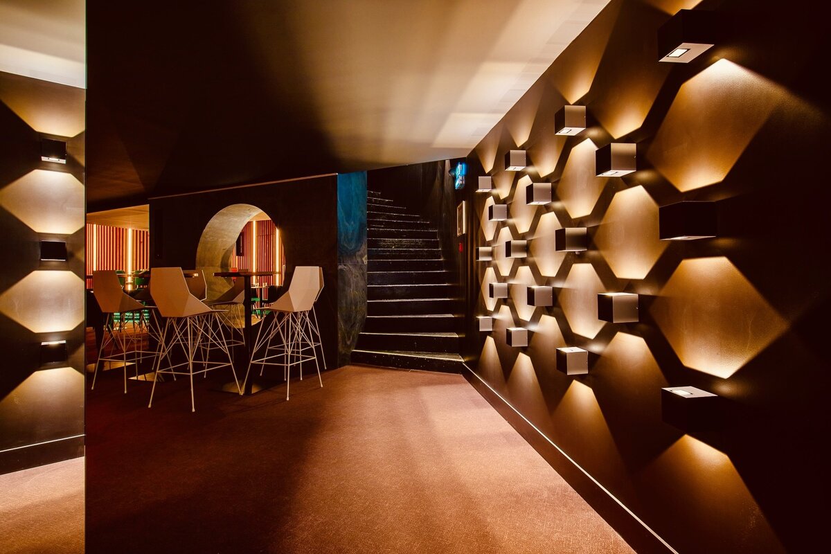A hallway with a staircase and a few tables and chairs