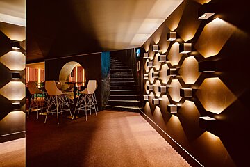 A hallway with a staircase and a few tables and chairs