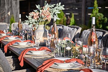 A table set with plates glasses and a vase of flowers