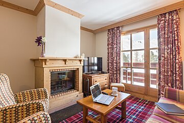 A living room with a fireplace and a laptop on a table