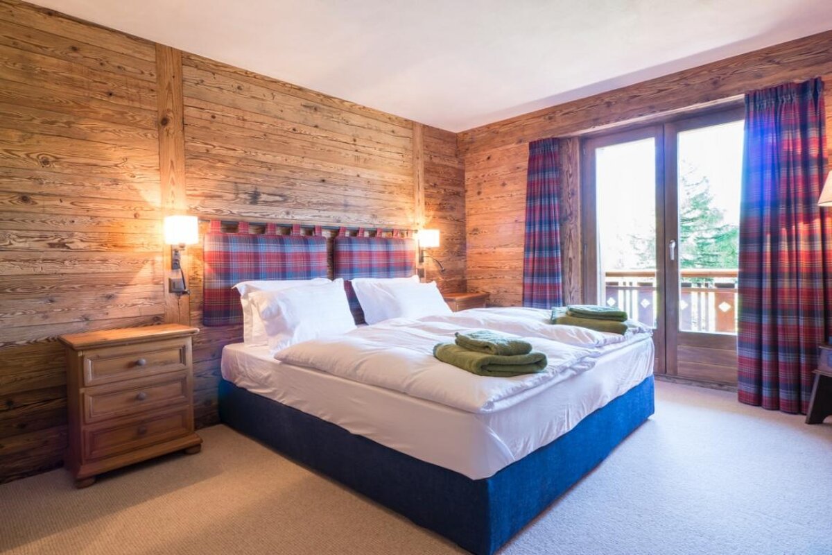 A bedroom with a bed and a window with plaid curtains