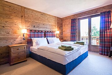 A bedroom with a bed and a window with plaid curtains