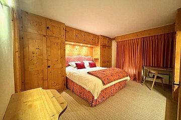 A bedroom with a large bed and a desk