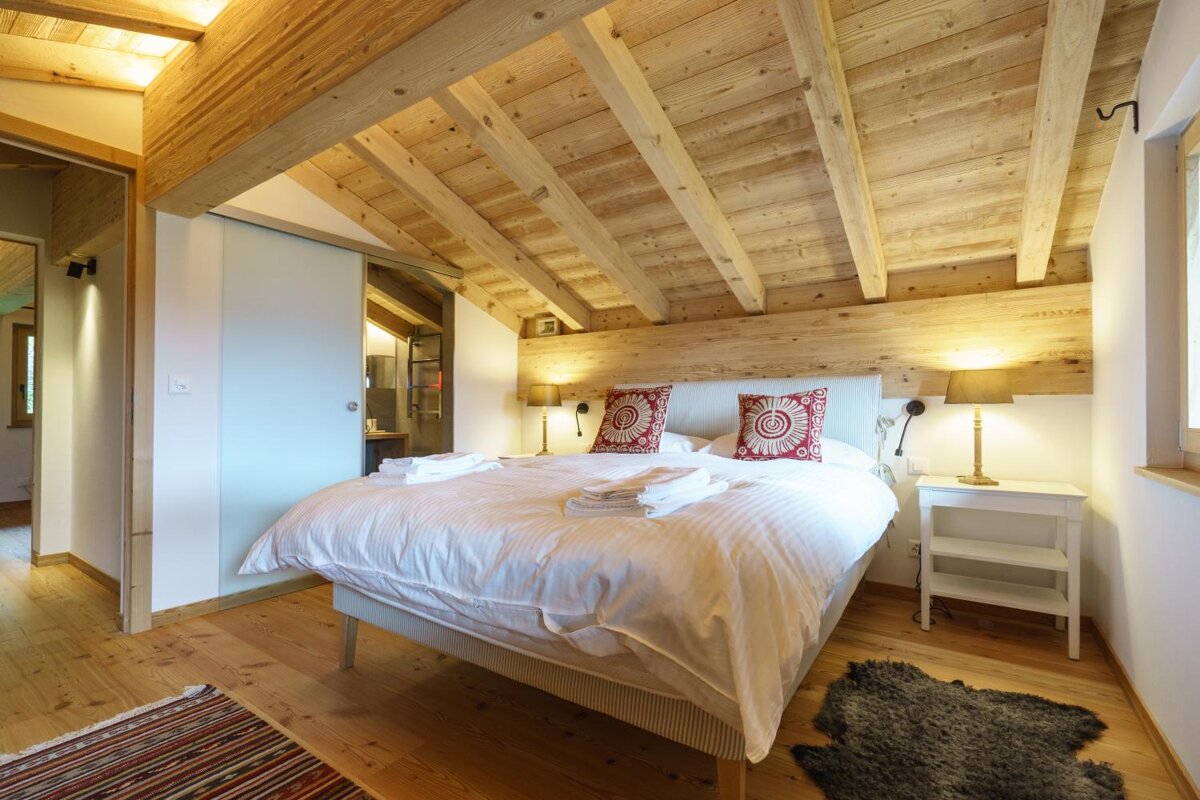 A bedroom with a wooden ceiling and a bed