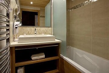 A bathroom with a sink , tub , mirror and towel rack
