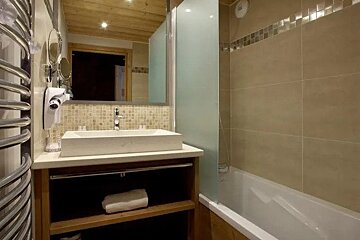 A bathroom with a sink , tub , mirror and towel rack