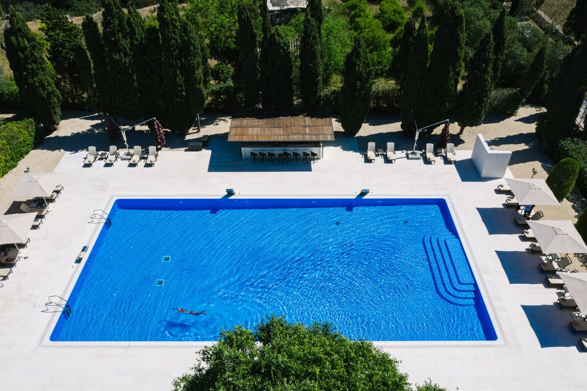 An aerial view of a large swimming pool surrounded by chairs and umbrellas