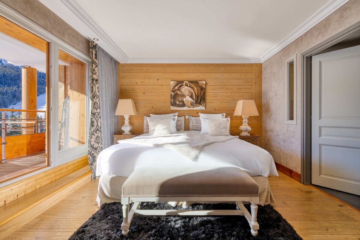 A bedroom with a painting on the wall above the bed