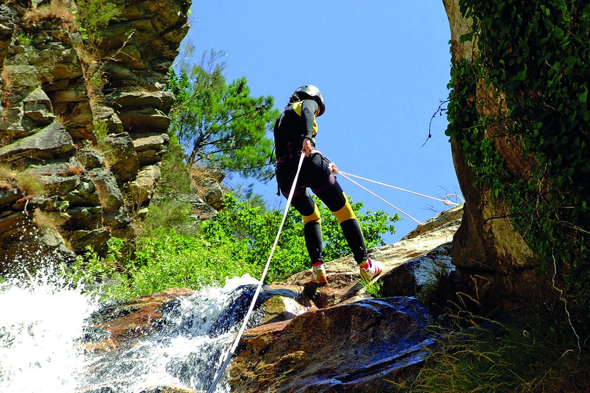 A person is hanging from a rope over a waterfall