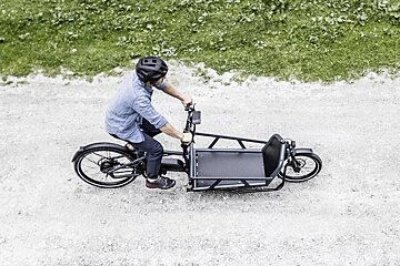 A man wearing a helmet is riding a cargo bike