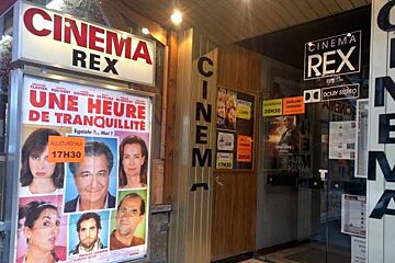 A movie poster is hanging on the side of a cinema