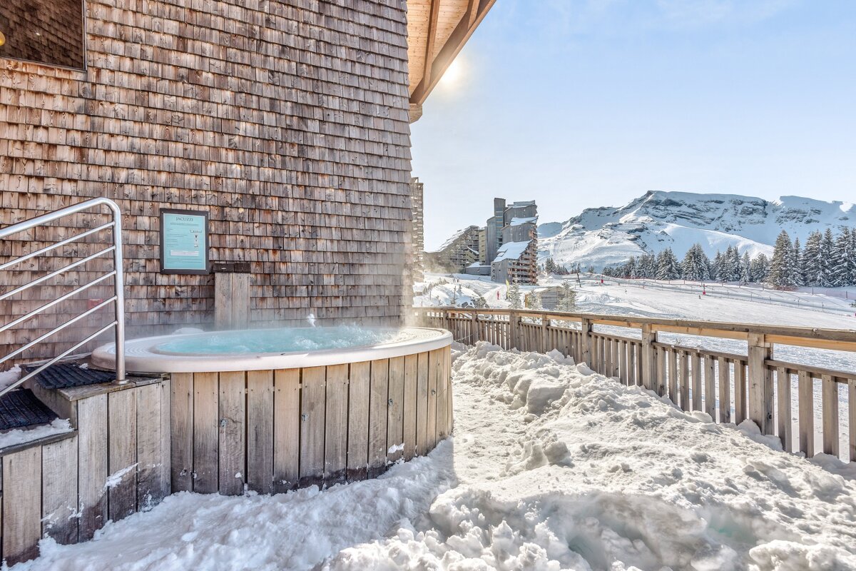 A hot tub in the snow outside of a building