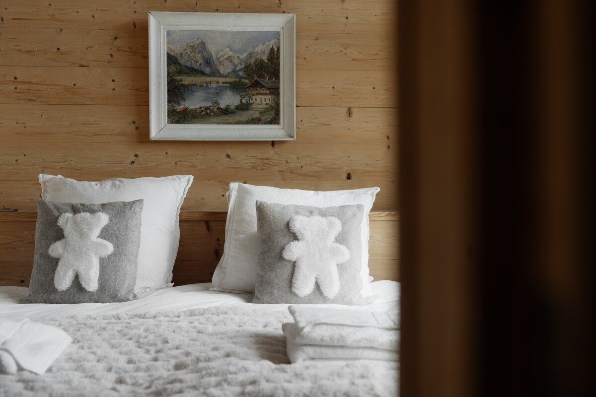 A painting hangs above a bed with teddy bear pillows