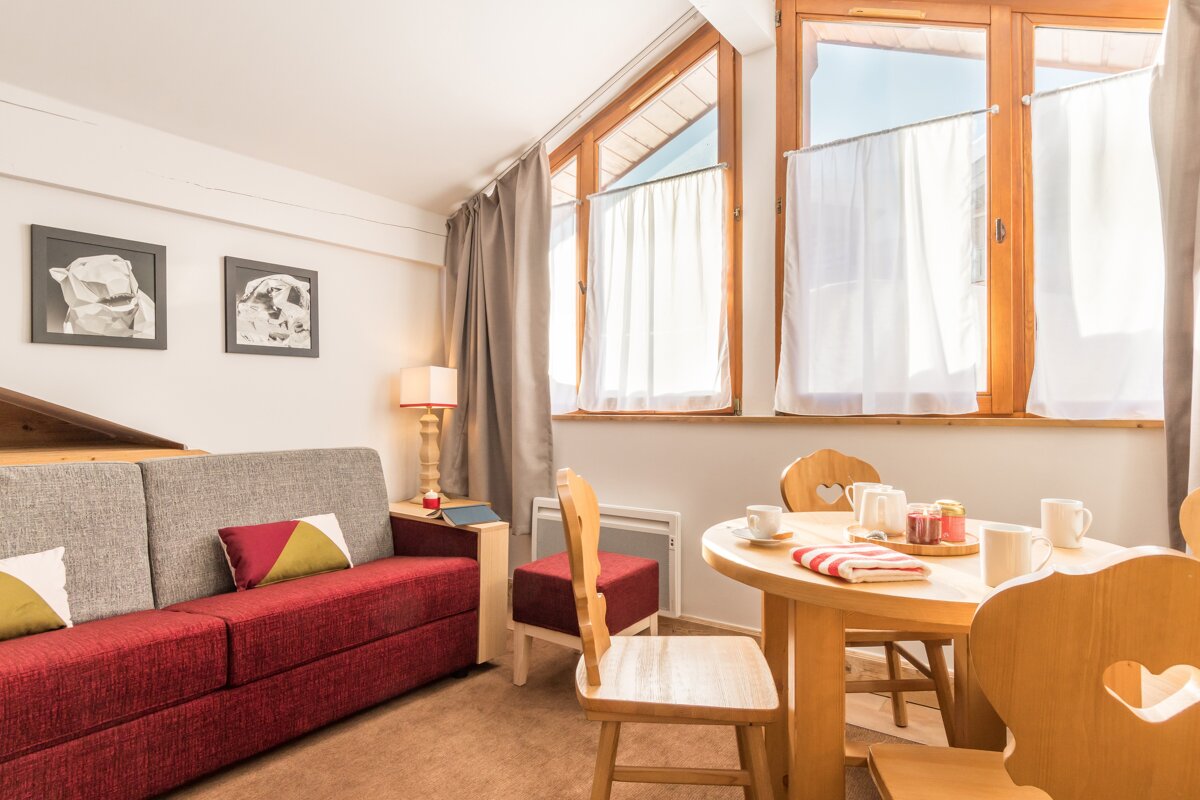 A living room with a red couch and a wooden table