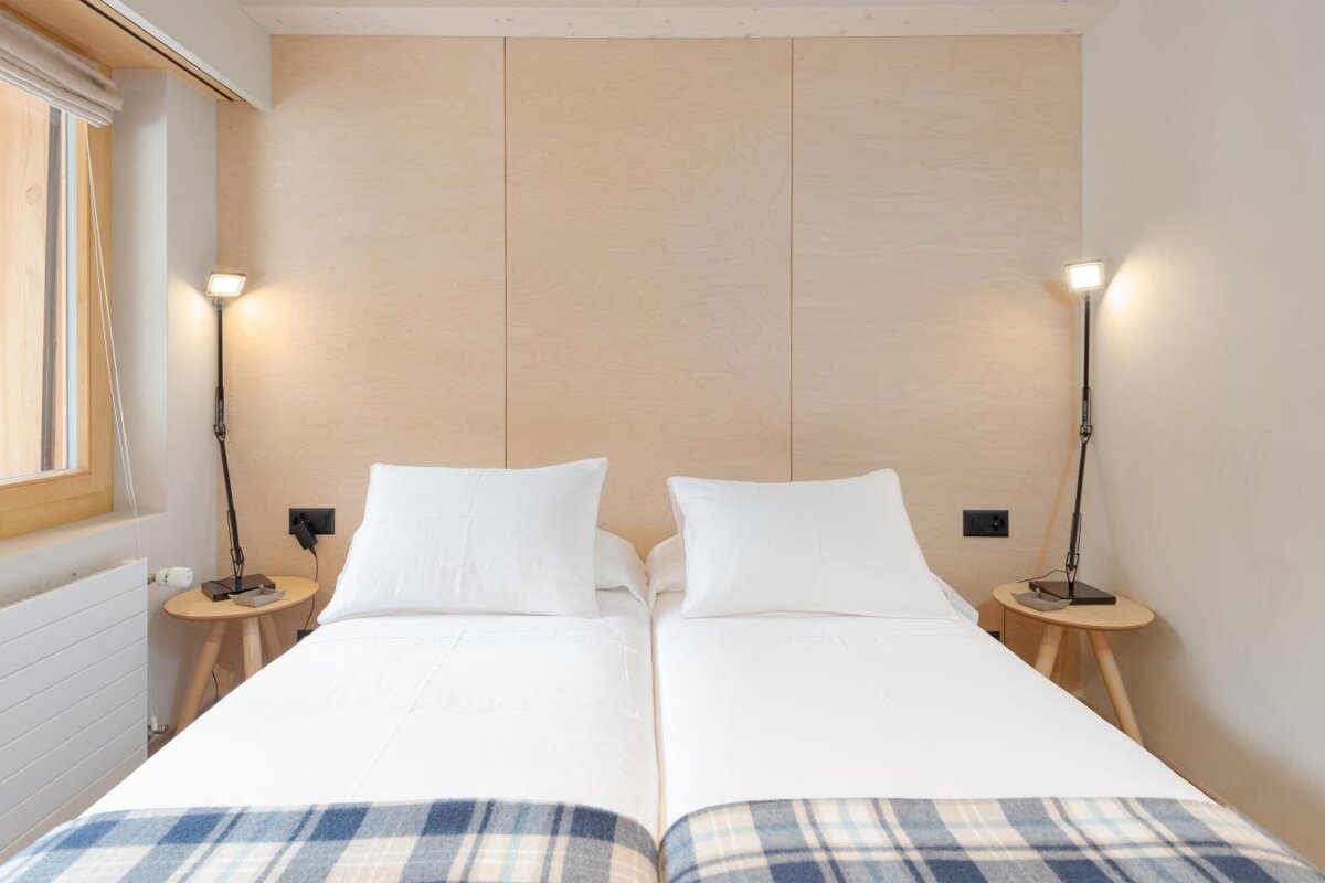 A bedroom with two beds and two lamps