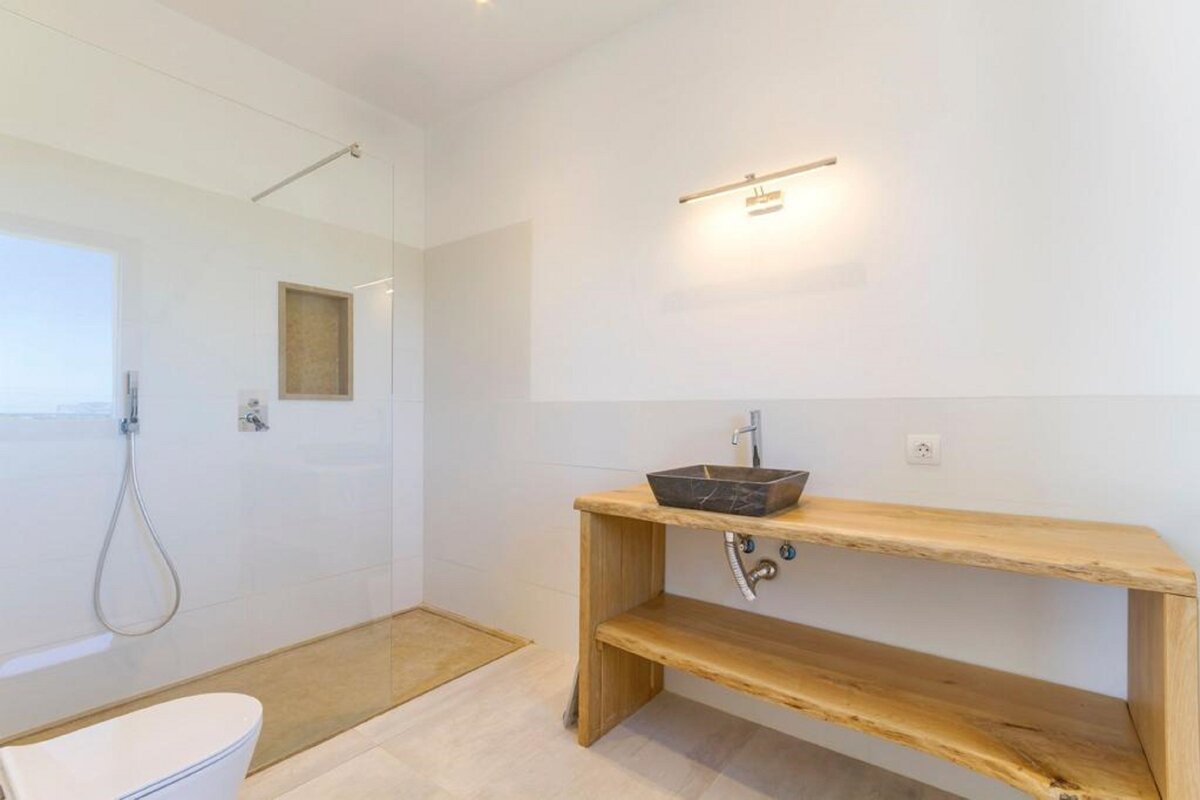 A bathroom with a walk in shower and a sink