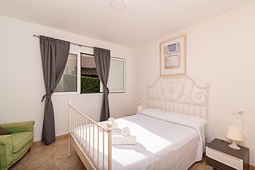 A bedroom with a bed and a green chair