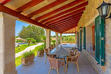 A patio with a table and chairs under a wooden roof