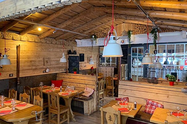 A restaurant with wooden tables and chairs and a chalkboard