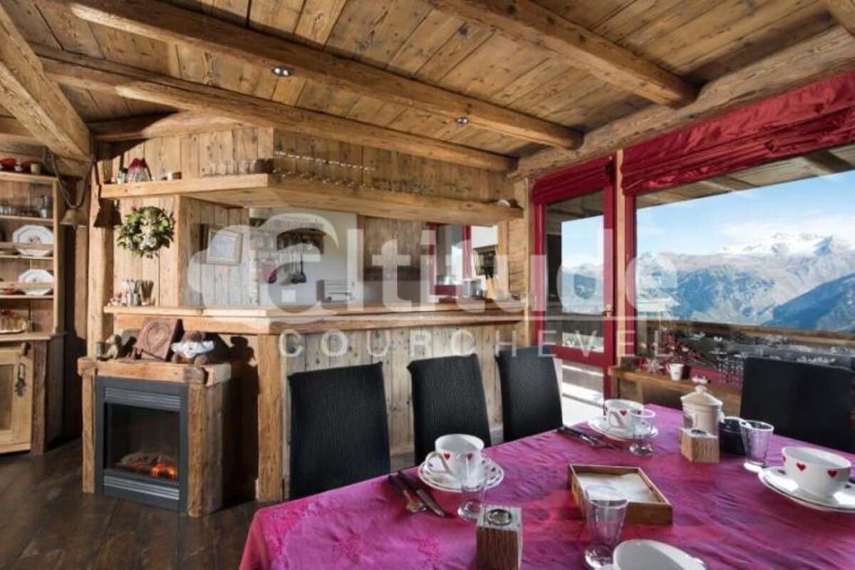 A dining room table with a pink table cloth and a fireplace with a sign that says altitude courchevel