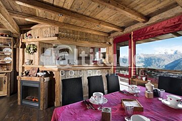 A dining room table with a pink table cloth and a fireplace with a sign that says altitude courchevel