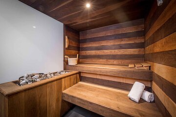 A wooden sauna with a bucket and towels on the bench