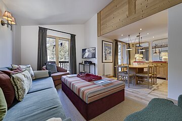 A living room with a blue couch and a red ottoman
