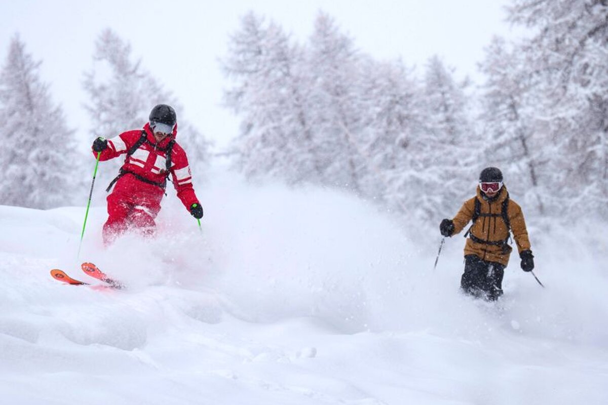 Two skiers are going down a snow covered slope