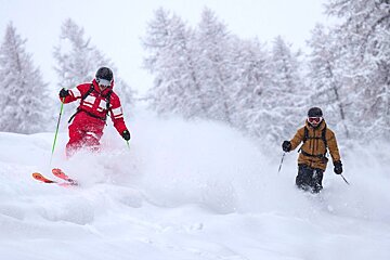 Two skiers are going down a snow covered slope