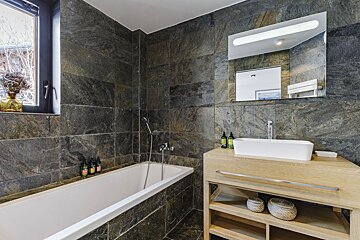 A bathroom with a bathtub sink and mirror