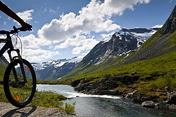 A person riding a bike in the mountains near a river