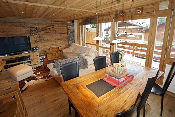 A living room with a table and chairs and a flat screen tv
