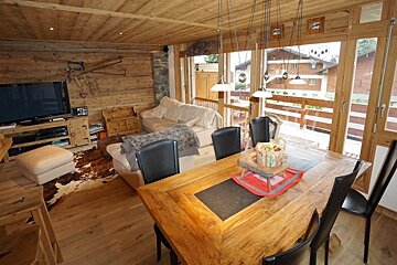 A living room with a table and chairs and a flat screen tv