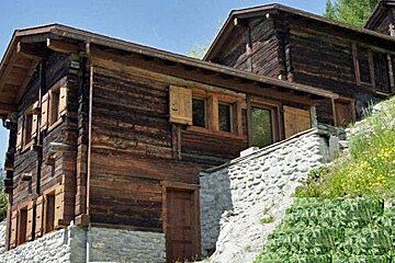 A large wooden house is sitting on top of a rocky hill