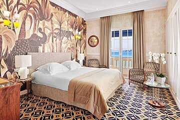 A hotel room with a king size bed and chairs