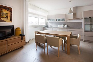 A kitchen with a table and chairs and a tv