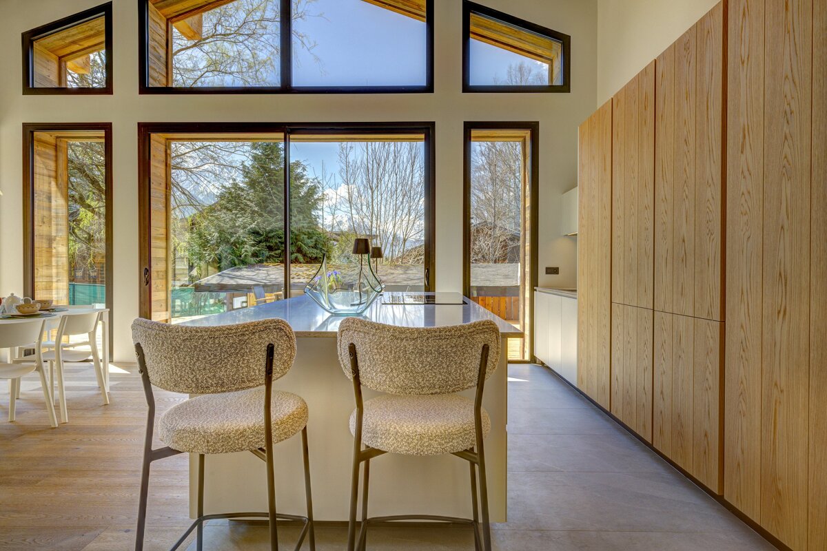 A kitchen with two stools and a large window