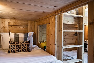 A wooden bunk bed with a ladder leading up to it